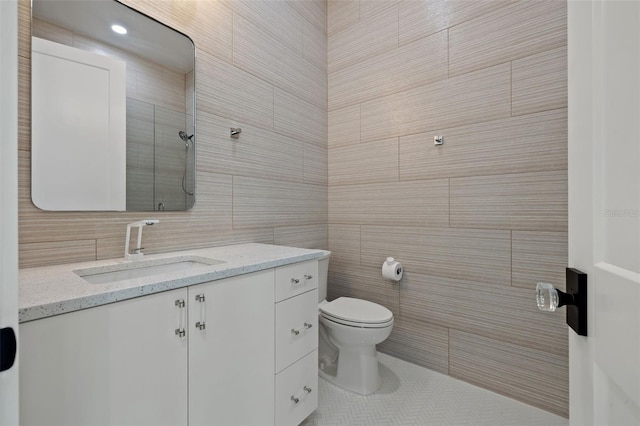 bathroom with vanity, a shower, toilet, tile walls, and tasteful backsplash