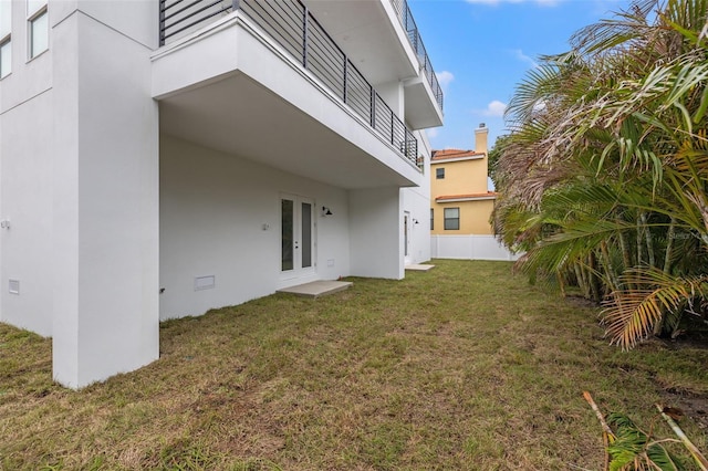 view of yard with french doors and a balcony