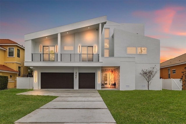 contemporary home featuring a lawn, a garage, and a balcony