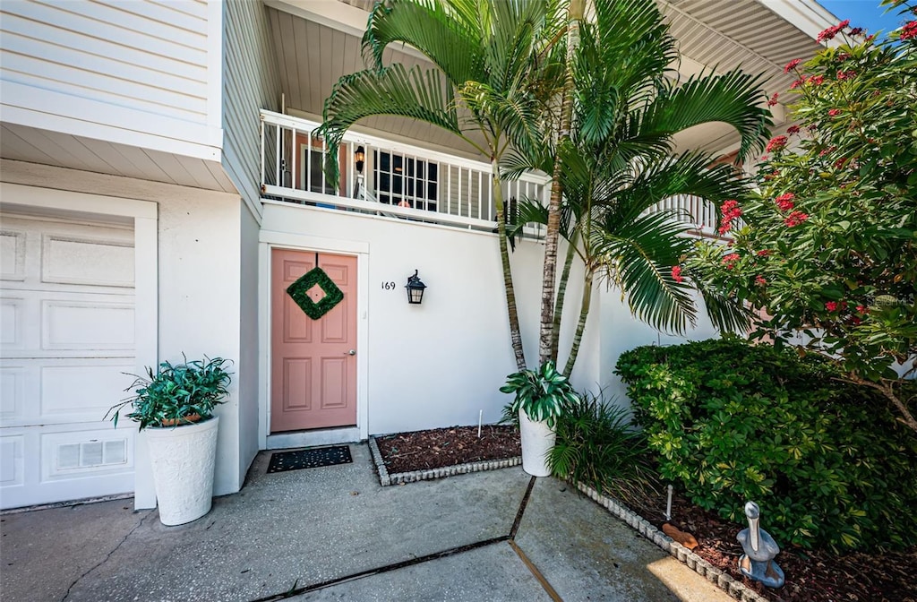 view of exterior entry with a balcony and a garage