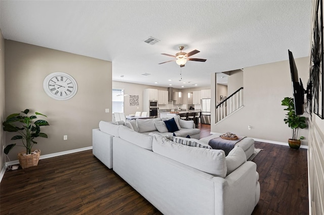 living room featuring a textured ceiling, ceiling fan, and dark wood-type flooring