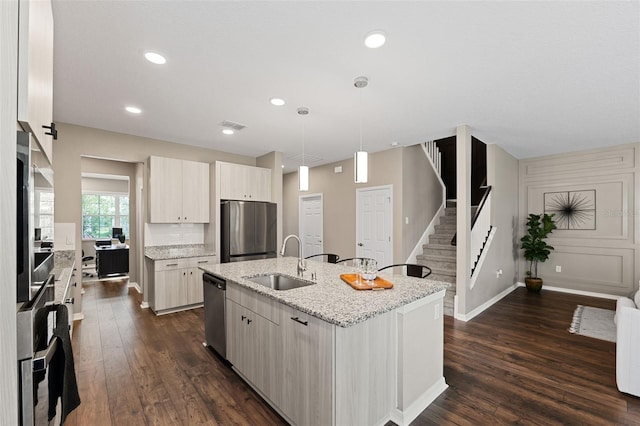 kitchen with sink, stainless steel appliances, dark hardwood / wood-style floors, decorative light fixtures, and a kitchen island with sink