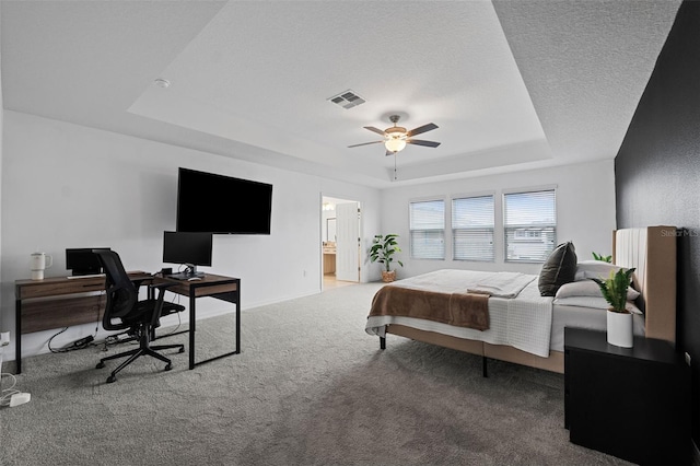 bedroom featuring carpet flooring, a textured ceiling, a tray ceiling, ceiling fan, and connected bathroom