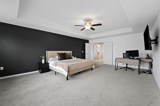 carpeted bedroom with ceiling fan and a raised ceiling