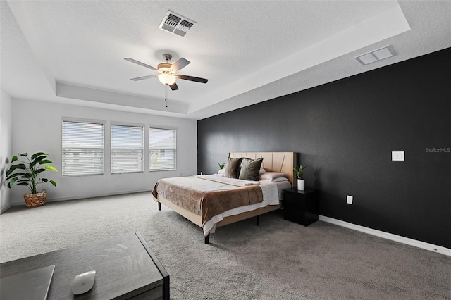 bedroom with carpet, ceiling fan, a raised ceiling, and a textured ceiling