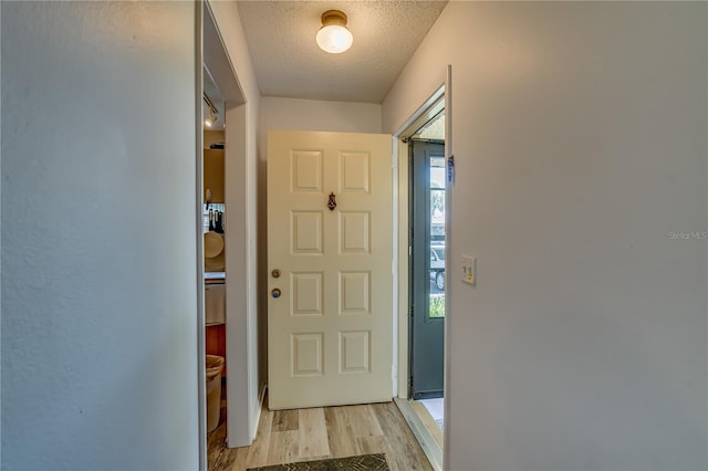 doorway to outside featuring light hardwood / wood-style flooring and a textured ceiling