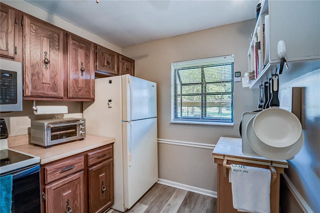 kitchen with range with electric cooktop, white fridge, and light hardwood / wood-style floors