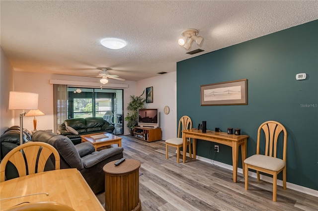 living room featuring ceiling fan, hardwood / wood-style floors, and a textured ceiling