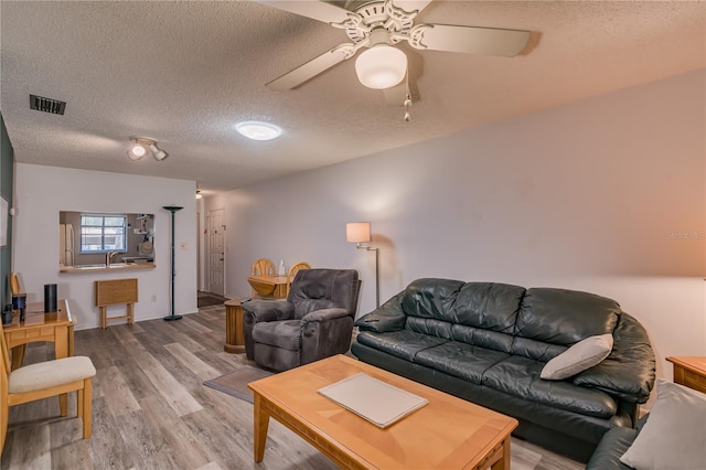 living room with ceiling fan, wood-type flooring, and a textured ceiling