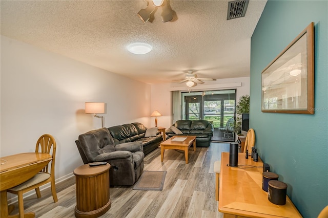 living room with a textured ceiling, wood-type flooring, and ceiling fan