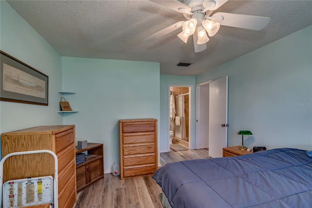 bedroom with ceiling fan, ensuite bathroom, light hardwood / wood-style floors, and a textured ceiling