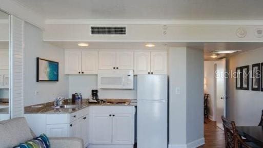 kitchen featuring white appliances, white cabinetry, crown molding, and sink