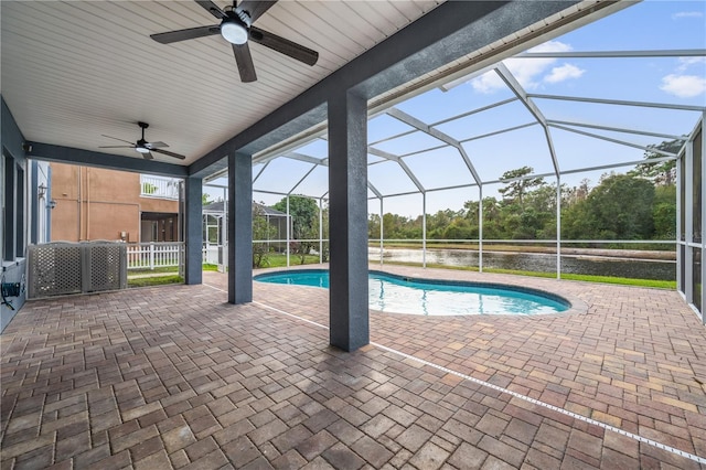 view of swimming pool with ceiling fan, a water view, glass enclosure, and a patio area