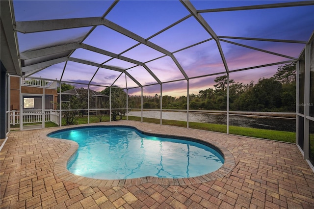 pool at dusk featuring a patio and a lanai