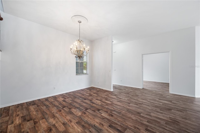 empty room featuring dark wood-type flooring and a chandelier