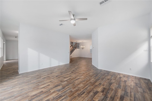 spare room featuring dark wood-type flooring and ceiling fan with notable chandelier