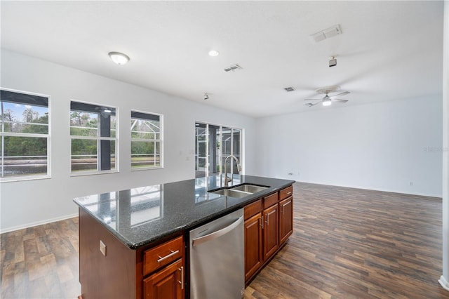 kitchen with dishwasher, sink, dark stone countertops, dark hardwood / wood-style flooring, and a center island with sink