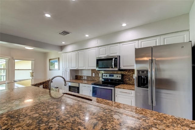 kitchen featuring decorative backsplash, appliances with stainless steel finishes, sink, dark stone countertops, and white cabinetry