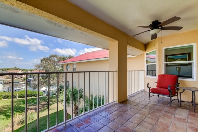 balcony with ceiling fan and a water view