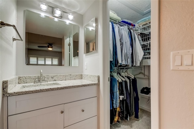 bathroom with a textured ceiling, vanity, and ceiling fan