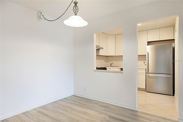 kitchen featuring sink, white cabinetry, decorative light fixtures, light hardwood / wood-style flooring, and stainless steel fridge