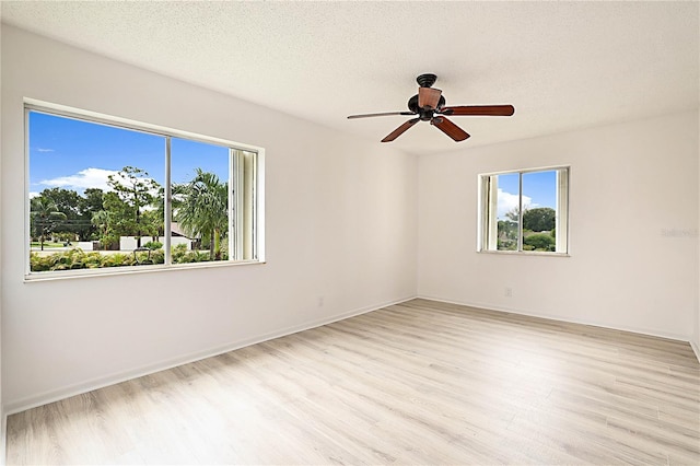 empty room with ceiling fan, a textured ceiling, and light hardwood / wood-style flooring