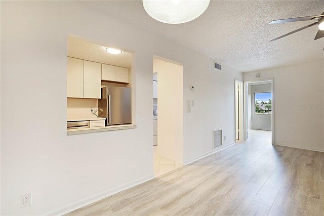 spare room with ceiling fan, light hardwood / wood-style floors, and a textured ceiling