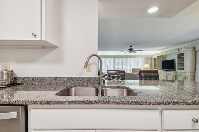 kitchen with dishwasher, dark stone counters, white cabinets, sink, and ceiling fan