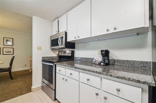 kitchen featuring dark stone counters, light colored carpet, a textured ceiling, white cabinets, and appliances with stainless steel finishes