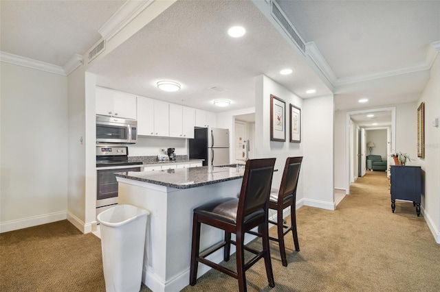 kitchen with white cabinetry, stainless steel appliances, light carpet, and ornamental molding