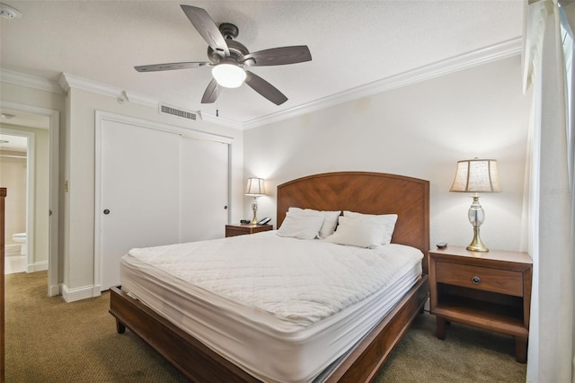 bedroom with ceiling fan, dark carpet, ornamental molding, and a closet