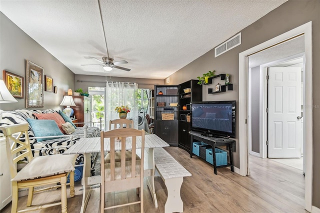 dining area featuring ceiling fan, light hardwood / wood-style flooring, separate washer and dryer, and a textured ceiling