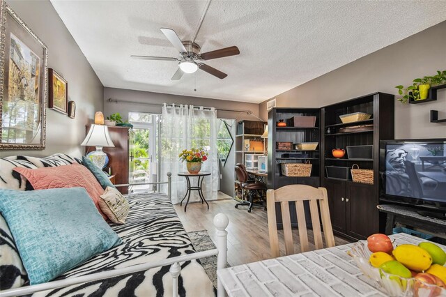 living room featuring a textured ceiling, ceiling fan, and light hardwood / wood-style floors