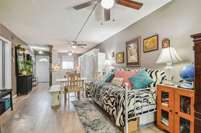 bedroom with ceiling fan, wood-type flooring, white refrigerator, and a textured ceiling