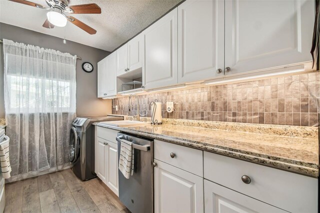 kitchen featuring washer / clothes dryer, stainless steel dishwasher, decorative backsplash, light wood-type flooring, and white cabinetry