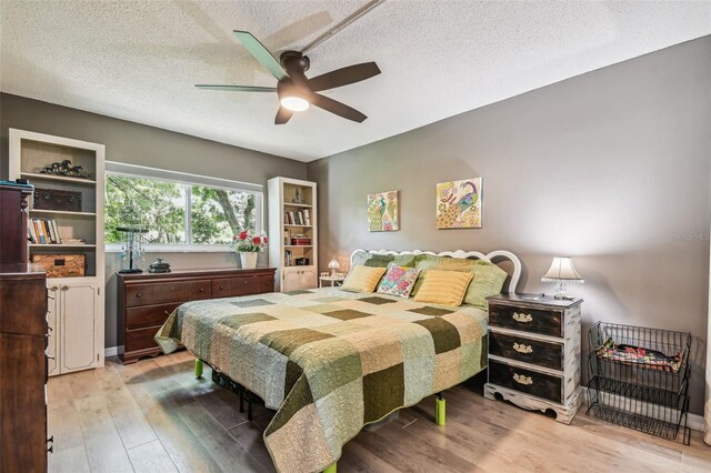 bedroom with a textured ceiling, ceiling fan, and light wood-type flooring