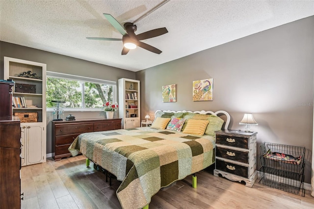 bedroom featuring hardwood / wood-style flooring, ceiling fan, and a textured ceiling