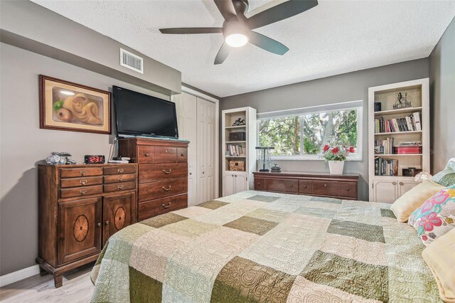 bedroom featuring a closet, a textured ceiling, ceiling fan, and light wood-type flooring