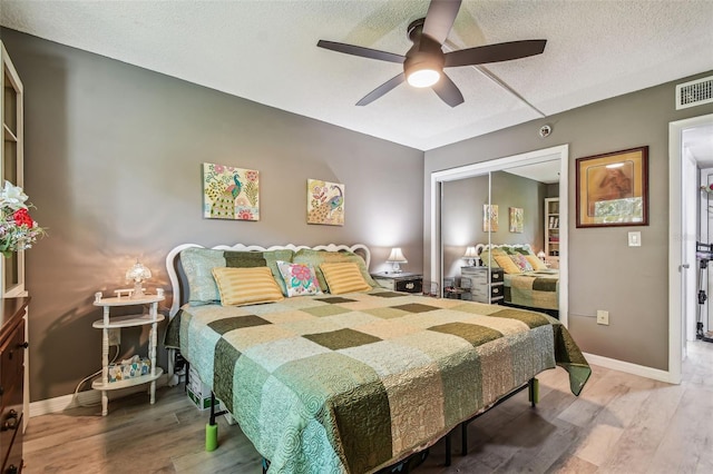 bedroom with a closet, a textured ceiling, hardwood / wood-style floors, and ceiling fan