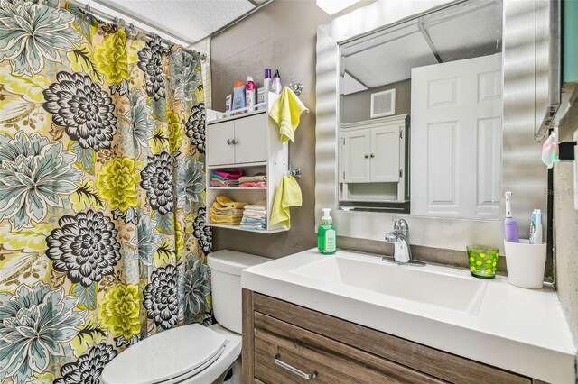 bathroom with toilet, vanity, and a textured ceiling