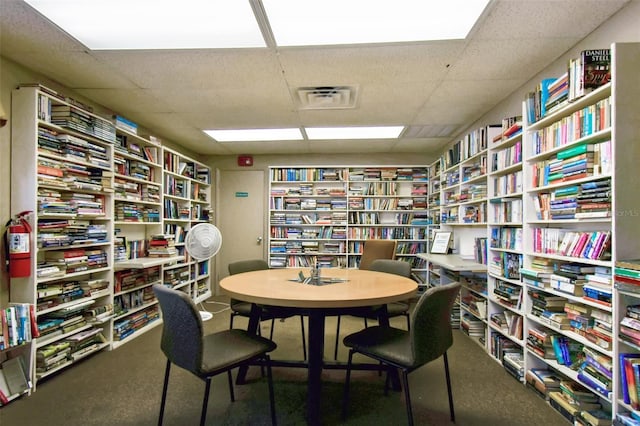 carpeted home office with a drop ceiling