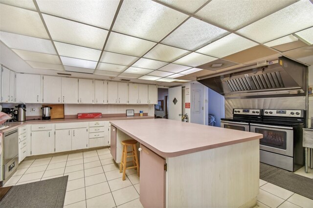 kitchen featuring a kitchen bar, appliances with stainless steel finishes, light tile patterned floors, a kitchen island, and custom range hood