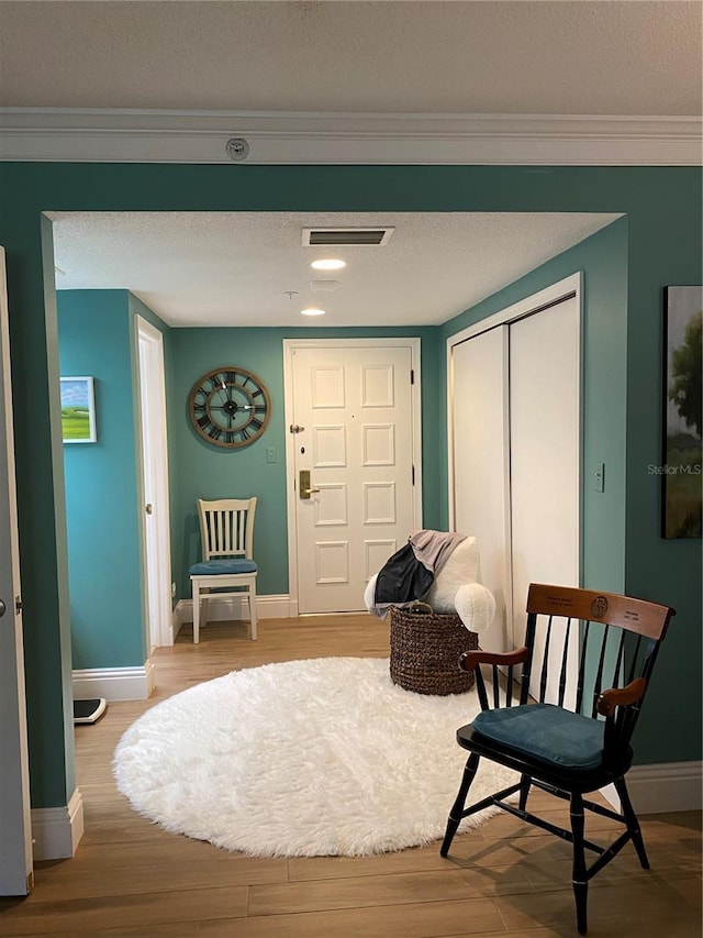 sitting room featuring crown molding, a textured ceiling, and light hardwood / wood-style flooring