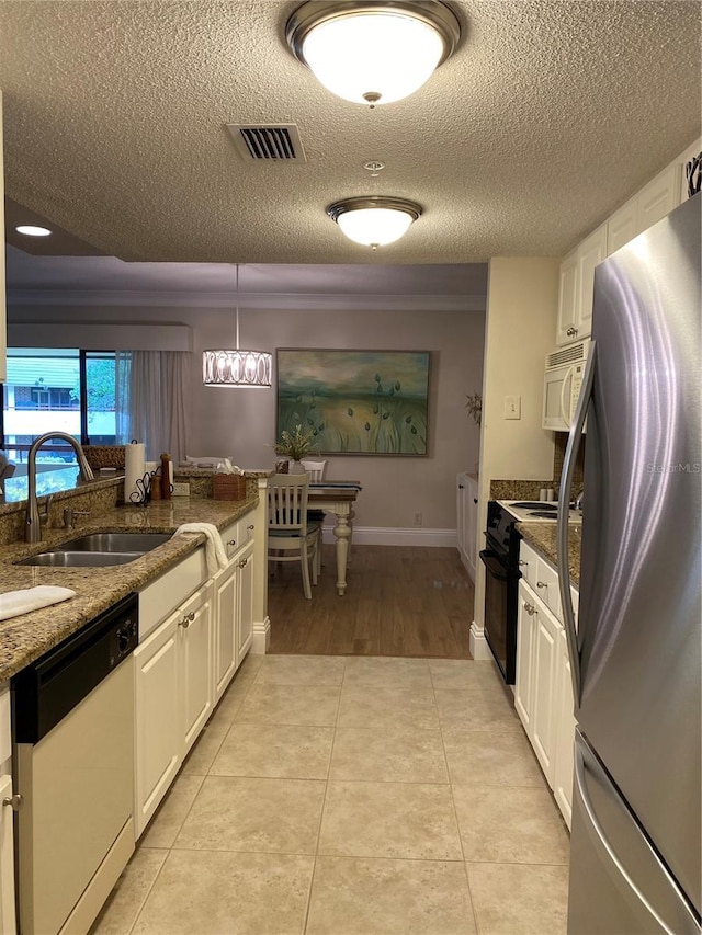 kitchen featuring sink, white appliances, white cabinetry, hanging light fixtures, and light tile patterned flooring