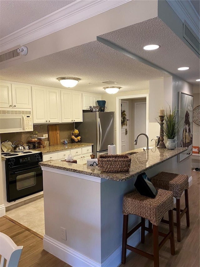 kitchen featuring crown molding, light hardwood / wood-style flooring, electric range, stainless steel refrigerator, and white cabinets