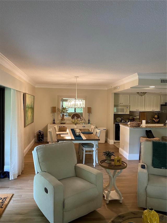 living room featuring crown molding, light wood-type flooring, a textured ceiling, and an inviting chandelier