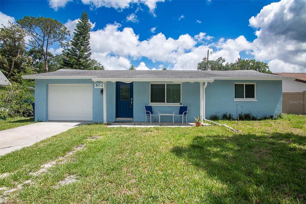 ranch-style home with an attached garage, a front lawn, a porch, and stucco siding