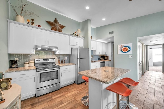 kitchen featuring light stone counters, a center island, white cabinets, and stainless steel appliances