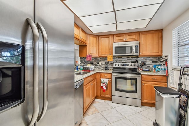 kitchen featuring stainless steel appliances, light tile flooring, tasteful backsplash, and sink