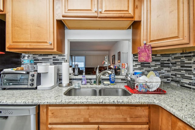 kitchen with sink, tasteful backsplash, dishwasher, and light stone counters